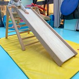 Enfant prêt à glisser le long du toboggan du triangle de motricité libre en bois