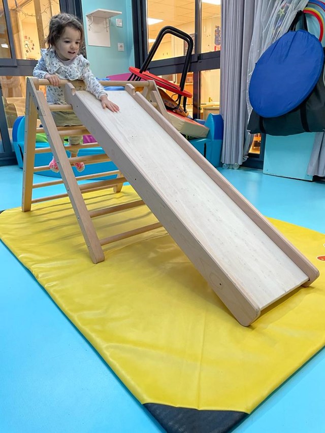 Enfant prêt à glisser le long du toboggan du triangle de motricité libre en bois
